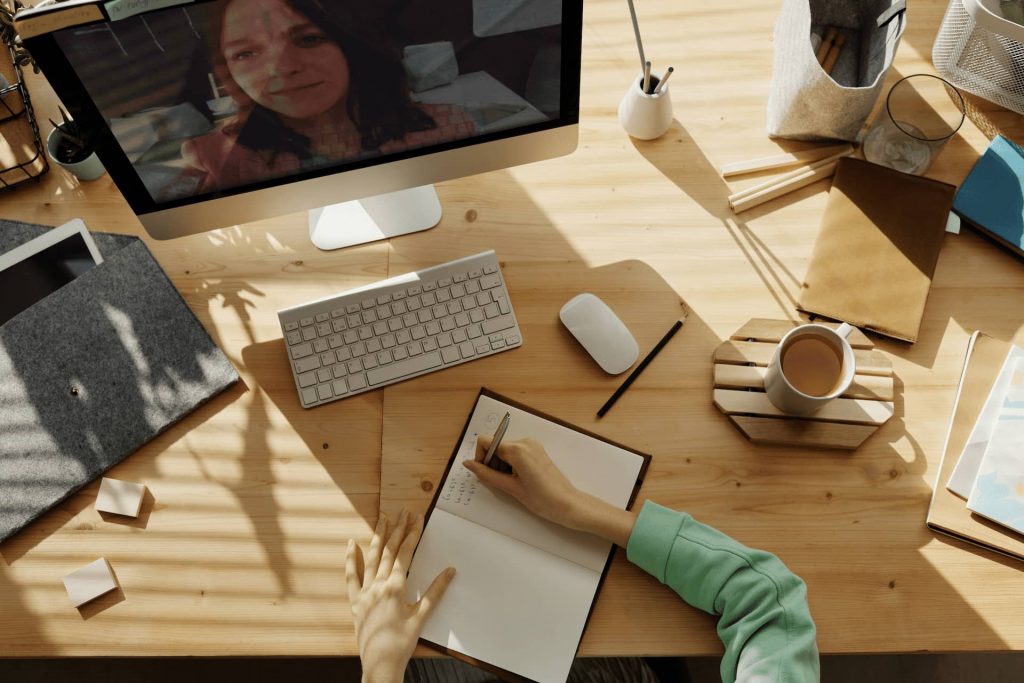 Person at desk in meeting writing in notebook.